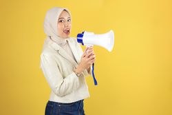 Happy Young Muslim Asian Woman is Announcing News or Discount Sale with Megaphone
