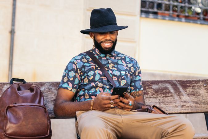 Stylish Black man in the city street using smartphone