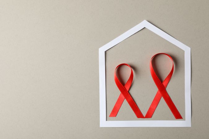 Awareness red ribbons in frame on grey cardboard background, copy space