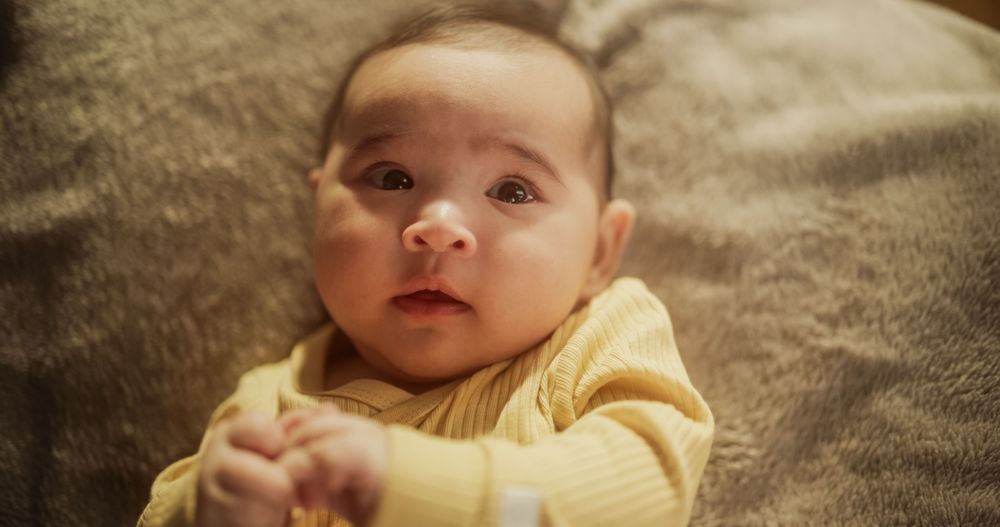 Portrait of a Cute Asian Baby Resting in a Crib, Surrounded by a Soft Blanket.