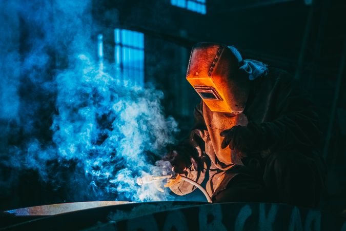 Tradesman wearing welding shield working indoor