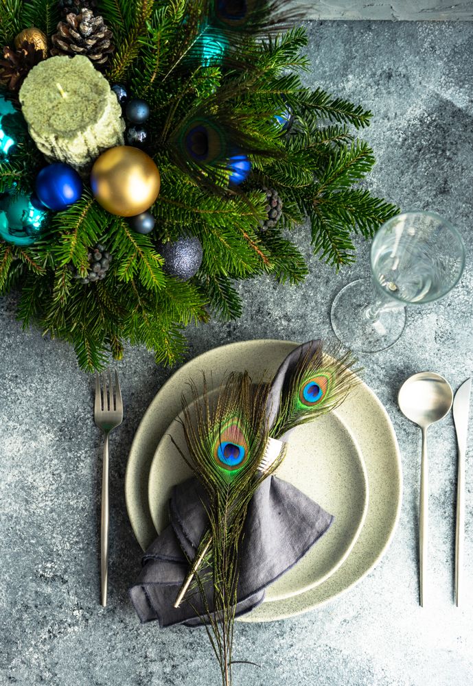 Top view of elegant festive table setting for Christmas dinner with peacock feathers