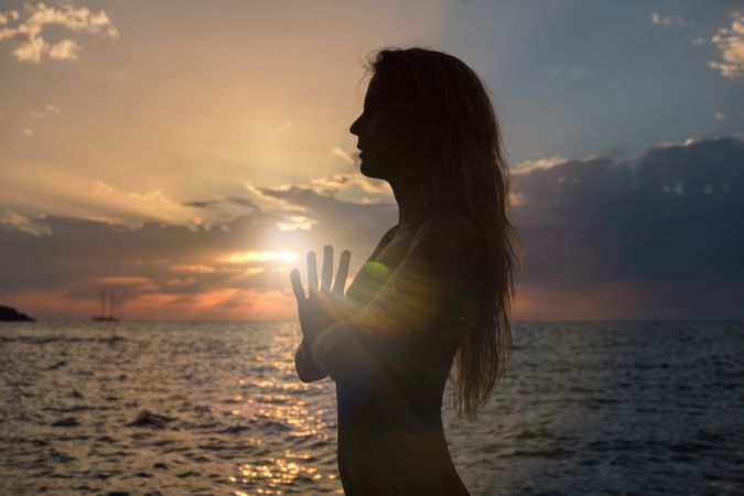 Unrecognizable woman practicing yoga in Mountain pose near sea i