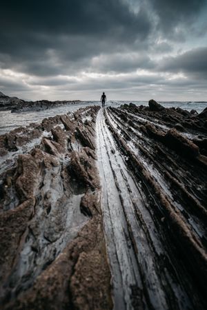 Anonymous person on rough stone shore