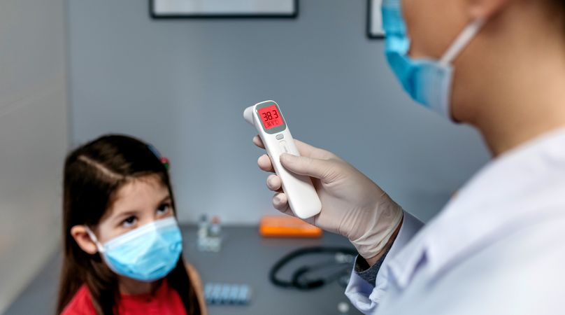 Female doctor looking at infrared thermometer after taking temperature to a girl
