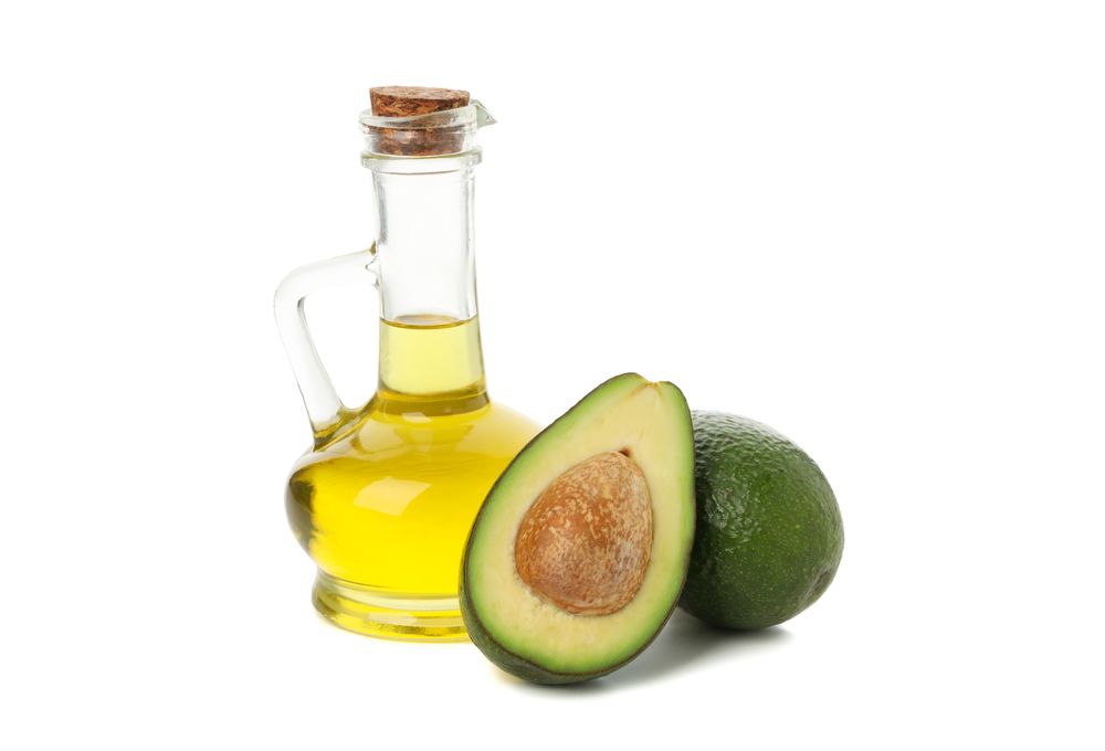 Ripe fresh avocado and oil isolated on blank background