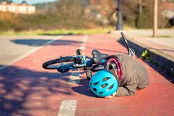 Boy in helmet on his side after falling off his bike
