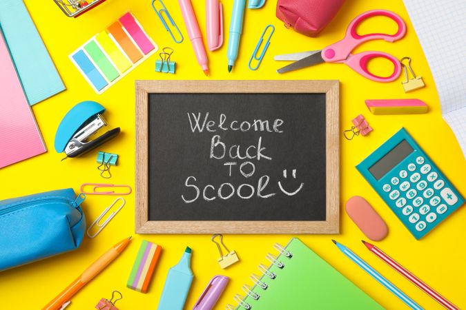 Text Welcome back to school and school supplies on yellow background