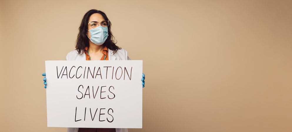 Healthcare worker with a signboard for indicating vaccination saves lives