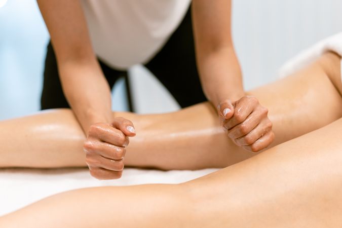 Massage therapist using her forearms to apply pressure to her client’s legs