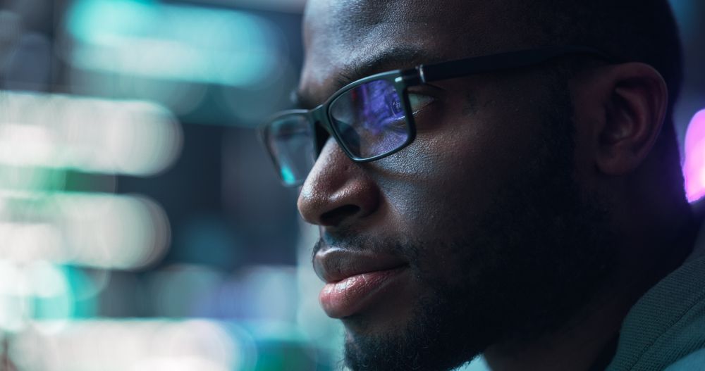Close Up Portrait of Black Man Working on Computer, Lines of Code Language Reflecting on his Glasses.