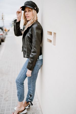 Stylish woman confidently leaning on white wall
