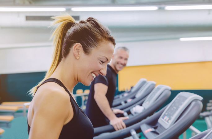 Smiling man and woman chatting between treadmills in gym