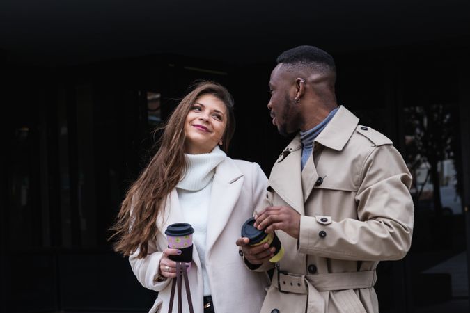 Happy multiethnic couple in stylish clothes with takeaway coffee
