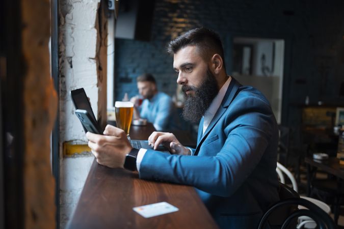 Man with phone and beer in pub
