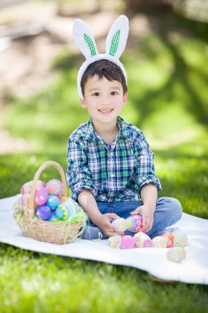 Biracial Baby Boy Outside Wearing Rabbit Ears Playing with Easter Eggs