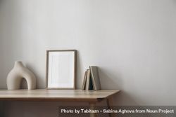 Blank poster on wooden table with empty vase and books 4ZG8xb