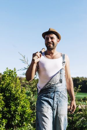 Smiling young farmer man standing in the garden while looking away