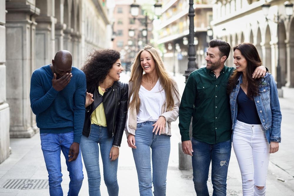 Laughing group of friends walking down city street