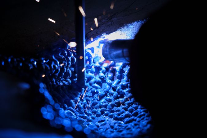 Worker welding metal around stick