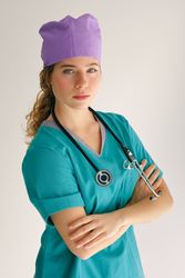 Woman in medical workwear with stethoscope against gray backdrop