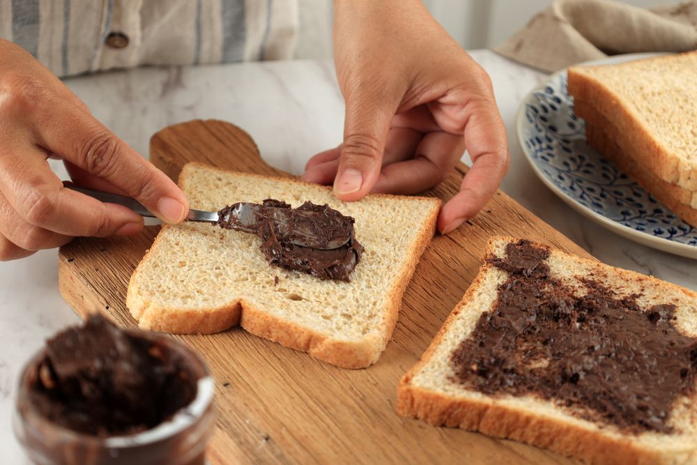 Spreading Chocolate Nut Butter on Sliced Bread