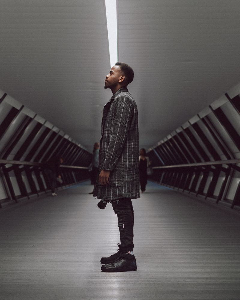 Man wearing coat standing in tunnel looking away