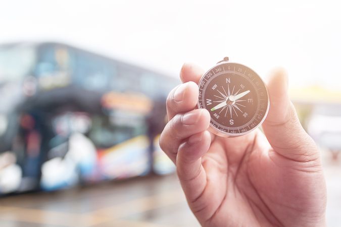 Compass in hand on blur of bus for background