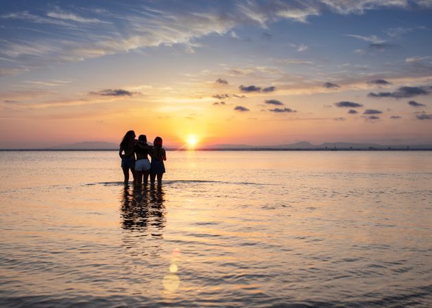 Women embracing on sunset at sea