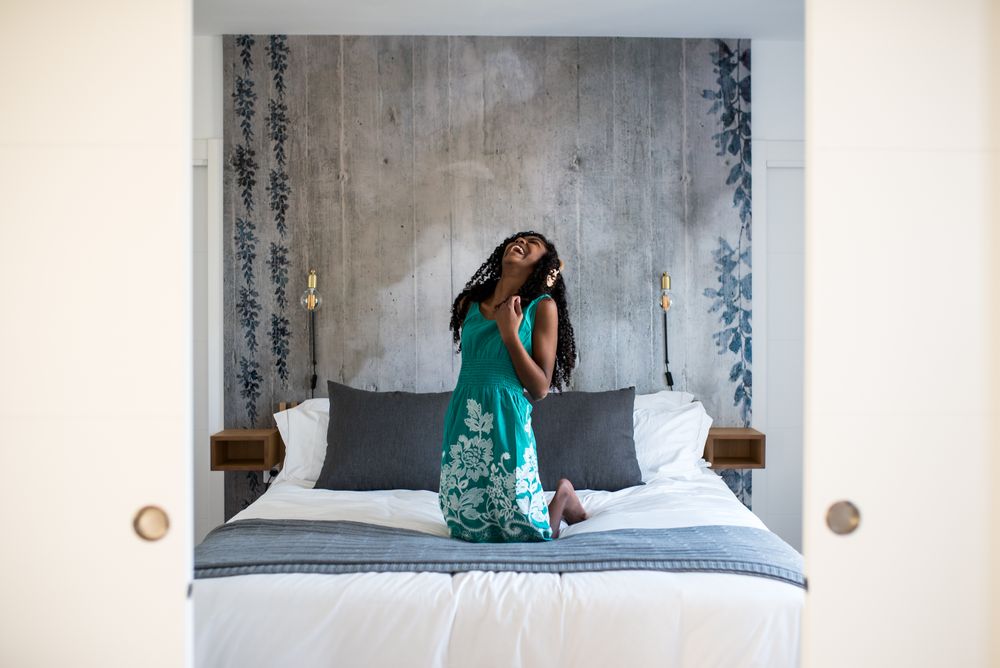 Black girl with headphones dancing on bed