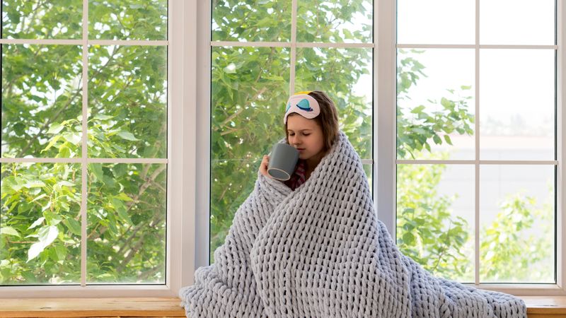 Girl sipping tea wrapped in a cozy blanket