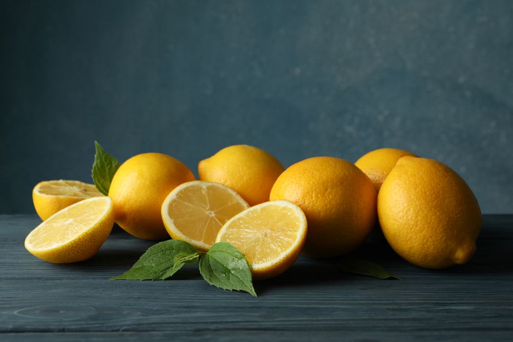 Fresh lemons and leaves on wooden table. Ripe fruit