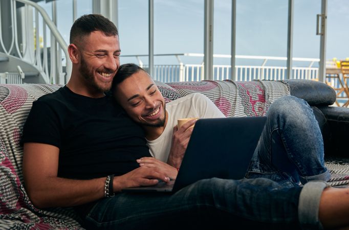 Happy gay couple using laptop at home
