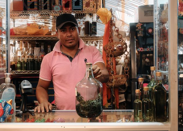 Man at store in Oaxaca with large vat of herbal tincture