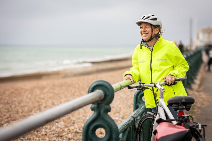 Happy mature woman enjoying coastal view from bike