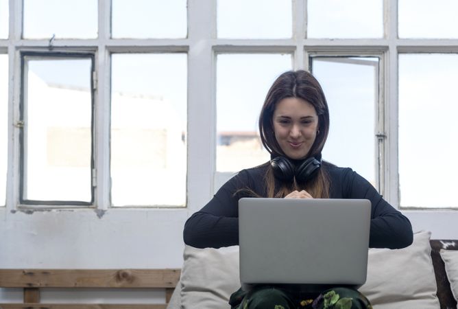 Business woman in headphones sitting with laptop at home