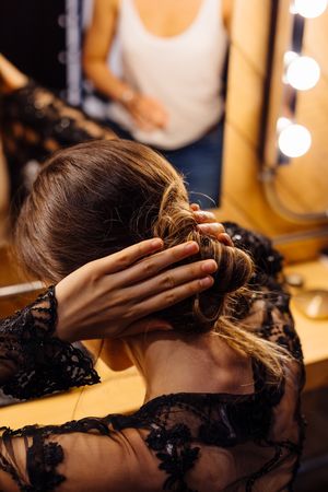 Female actress making hairstyle by illuminated mirror