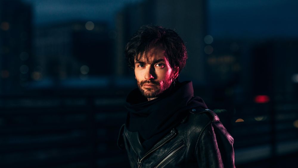 Sultry man in moody red lighting on a dark rooftop