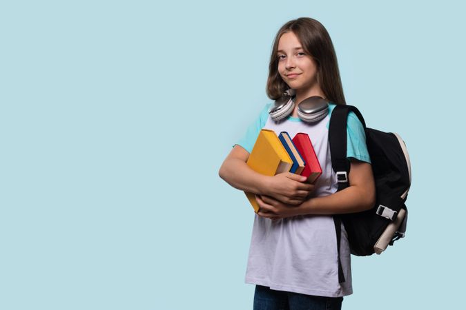 Young girl with backpack and books, ready for school