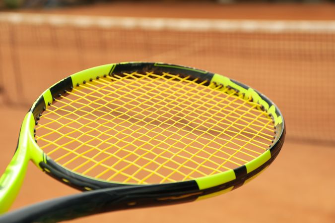 Tennis racquet against clay court, close up