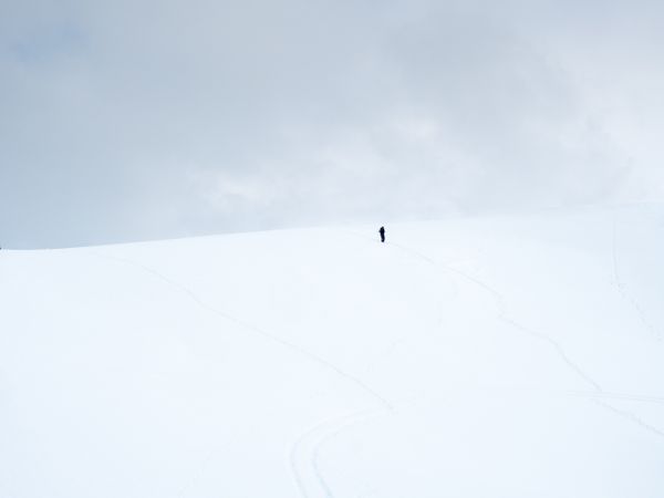Unrecognizable lonely traveler walking on snowy hill