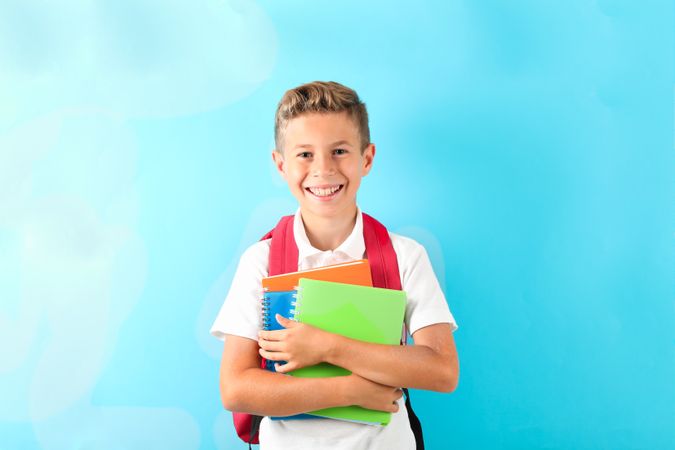 Boy with copybooks and backpack against color background, space for text