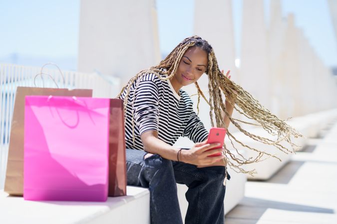 Content female taking selfie seated outside in pedestrian area