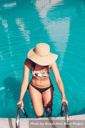 Woman in bikini with sun hat getting out of the pool 4Mk8x0