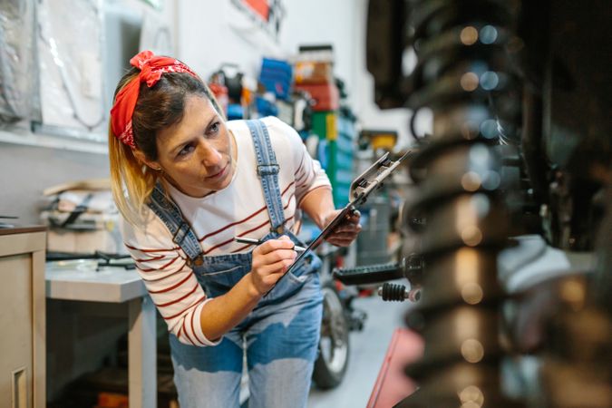 Mechanic woman filling out motorcycle documentation on garage
