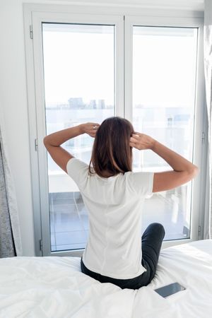 Woman getting up from bed stretching hands above head