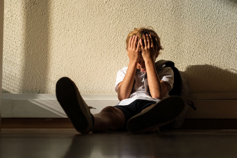 Lonely pupil covering face in classroom