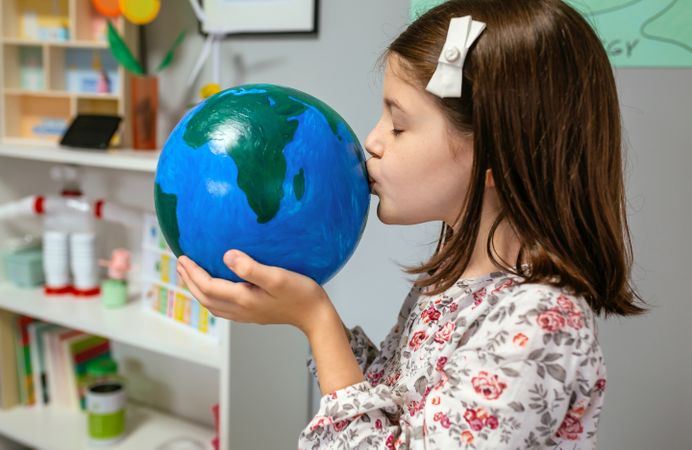 Female student kissing a handmade globe world at ecology classroom