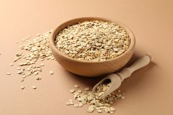 Bowl and scoop with oatmeal flakes on craft background