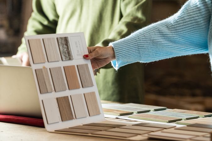 Anonymous woman choosing sample with carpenter in workshop